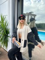 Denim ve krem renk detaylı cepli oversize hırka giyen bir kadın, modern ve rahat bir tarz sergiliyor.