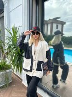 Denim ve krem renk detaylı cepli oversize hırka giyen bir kadın, modern ve rahat bir tarz sergiliyor.