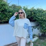 Denim detaylı triko kazak giyen, bordo tayt ve kürklü çizmelerle kombin yapan bir kadın. Kazak ekru rengiyle sade ve şık bir görünüm sunuyor.