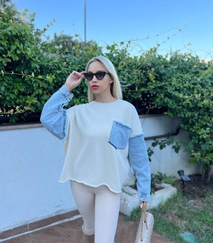 Denim detaylı triko kazak giyen, bordo tayt ve kürklü çizmelerle kombin yapan bir kadın. Kazak ekru rengiyle sade ve şık bir görünüm sunuyor.