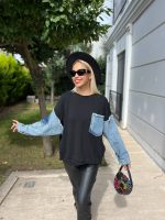 Denim detaylı triko kazak giyen, bordo tayt ve kürklü çizmelerle kombin yapan bir kadın. Kazak ekru rengiyle sade ve şık bir görünüm sunuyor.