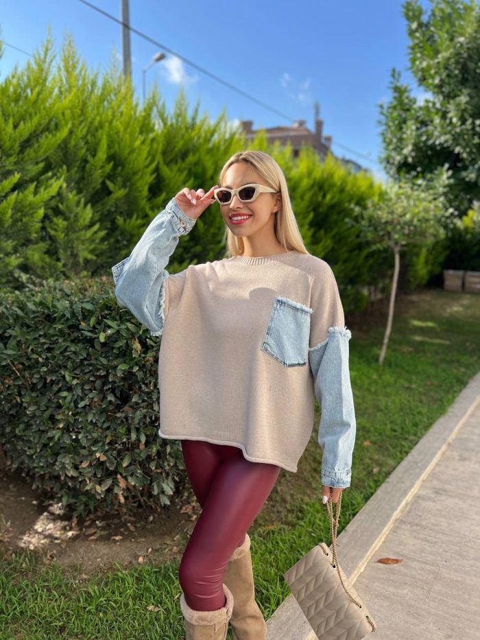 denim-detayli-triko-kazak-3 Denim detaylı triko kazak giyen, bordo tayt ve kürklü çizmelerle kombin yapan bir kadın. Kazak ekru rengiyle sade ve şık bir görünüm sunuyor.