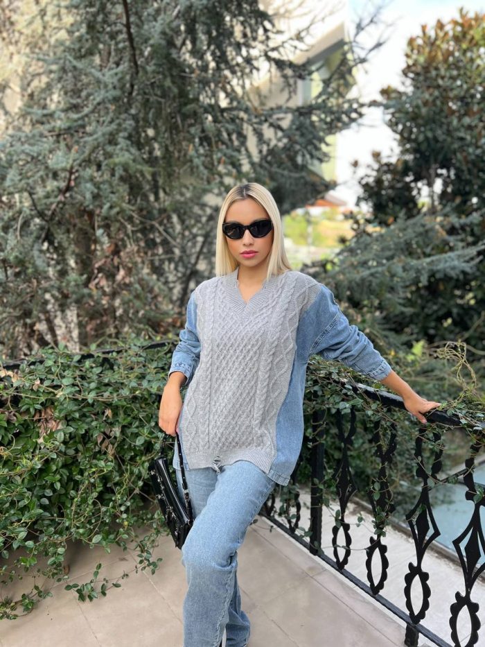 denim-kollu-orgu-desenli-triko-5 Denim kollu, örgü desenli krem renkli triko kazak giyen bir kadın, beyaz pantolon ve şık aksesuarlarla günlük kombinini tamamlıyor.