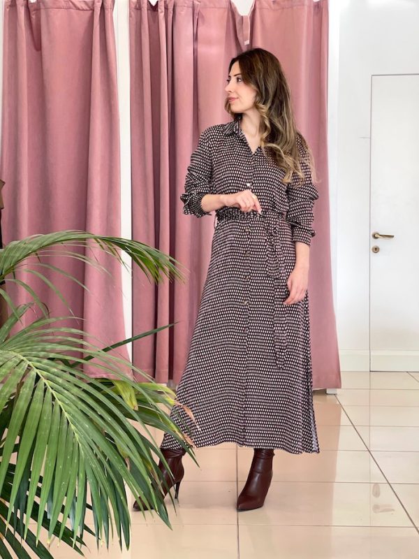 bordo ve beyaz desenli uzun kollu elbise giymiş bir kadın; belinde bağlama detayı ve kahverengi topuklu botlar.