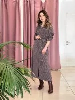 bordo ve beyaz desenli uzun kollu elbise giymiş bir kadın; belinde bağlama detayı ve kahverengi topuklu botlar.