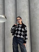 Ella Style lacivert baklava desenli oversize triko kazak giyen bir kadın. Kazağı, yırtık kot pantolon ve kırmızı detaylı bir çantayla kombinlemiş, kırmızı gözlüklerle şık bir dokunuş katmış.