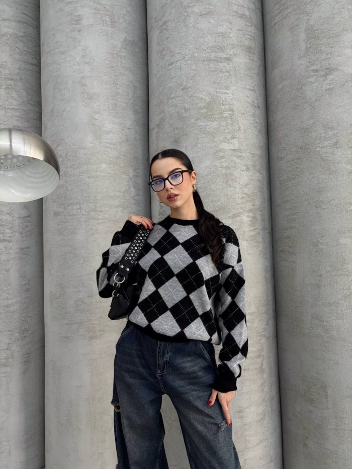 oversize-baklava-desenli-triko-kazak-1 Ella Style lacivert baklava desenli oversize triko kazak giyen bir kadın. Kazağı, yırtık kot pantolon ve kırmızı detaylı bir çantayla kombinlemiş, kırmızı gözlüklerle şık bir dokunuş katmış.
