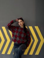 Ella Style lacivert baklava desenli oversize triko kazak giyen bir kadın. Kazağı, yırtık kot pantolon ve kırmızı detaylı bir çantayla kombinlemiş, kırmızı gözlüklerle şık bir dokunuş katmış.