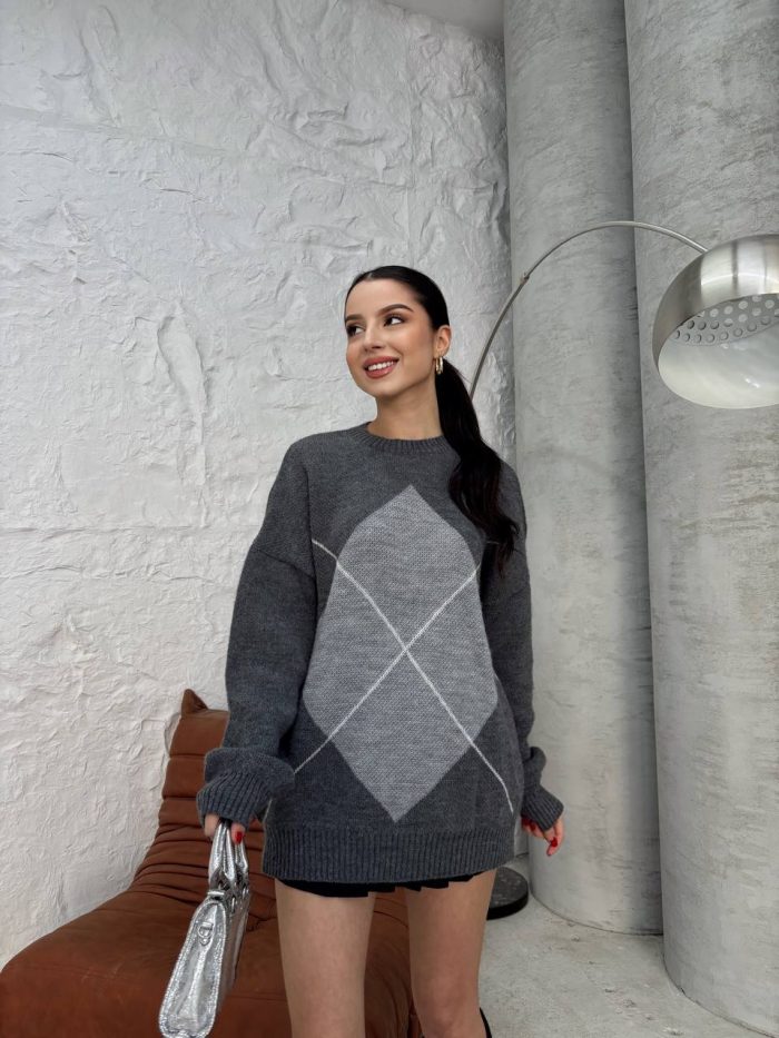oversize-baklava-desenli-triko-kazak-3 Ella Style gri baklava desenli oversize triko kazak giyen bir kadın. Kazağı siyah mini etek ve gümüş detaylı bir çantayla kombinlemiş.