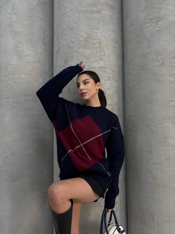 oversize-baklava-desenli-triko-kazak-5 Ella Style gri baklava desenli oversize triko kazak giyen bir kadın. Kazağı siyah mini etek ve gümüş detaylı bir çantayla kombinlemiş.