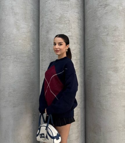 Ella Style gri baklava desenli oversize triko kazak giyen bir kadın. Kazağı siyah mini etek ve gümüş detaylı bir çantayla kombinlemiş.