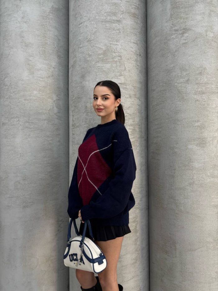 oversize-baklava-desenli-triko-kazak-6 Ella Style gri baklava desenli oversize triko kazak giyen bir kadın. Kazağı siyah mini etek ve gümüş detaylı bir çantayla kombinlemiş.