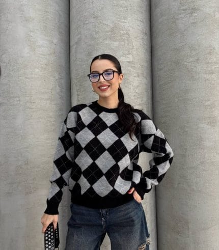 Ella Style lacivert baklava desenli oversize triko kazak giyen bir kadın. Kazağı, yırtık kot pantolon ve kırmızı detaylı bir çantayla kombinlemiş, kırmızı gözlüklerle şık bir dokunuş katmış.