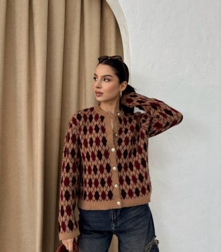 Ella Style pitikare ve baklava desenli siyah kadın hırka giyen bir kadın, bol kesim kot pantolon ve siyah çantayla kombin yapmış. Modern bir görünüm sağlayan gri beton sütunlar arka planda yer alıyor.