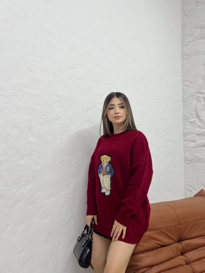sevimli-ayicik-islemeli-oversize-kazak-3 Ayıcık işlemeli bordo oversize kazak giyen bir kadın. Siyah mini etek, siyah çizmeler ve siyah el çantası ile kombinlenmiş.