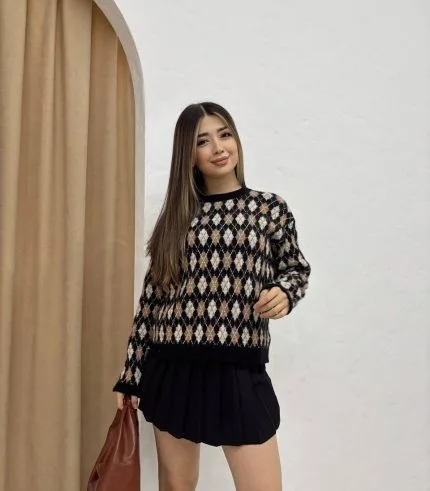 Baklava desenli bordo ve bej tonlarında yün kazak giyen bir kadın. Siyah mini etek, siyah çizme ve zincir detaylı siyah çantayla kombinlenmiş.